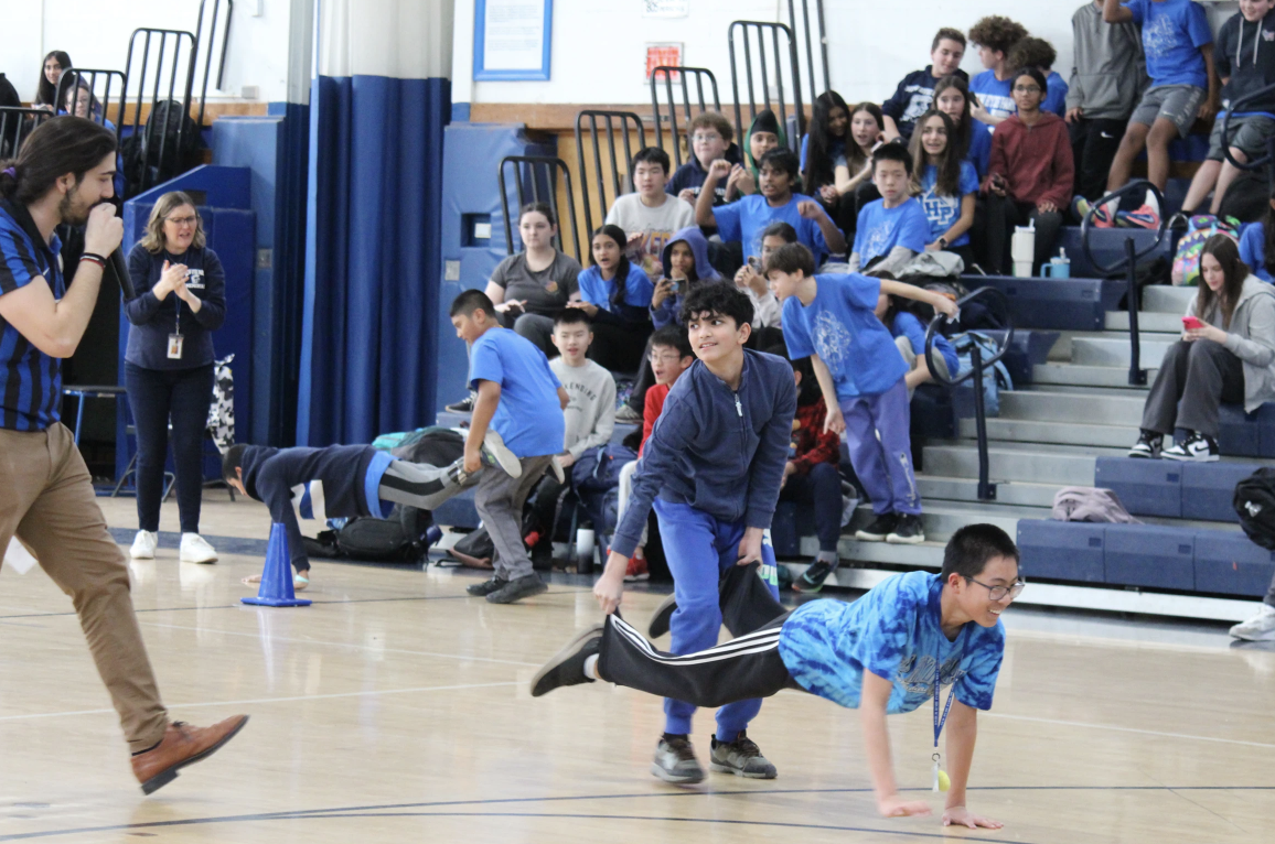 Agastya Arora talks to Mr. D'Ammassa while helping Jayden Jiang cross the finish line during the gym competition.